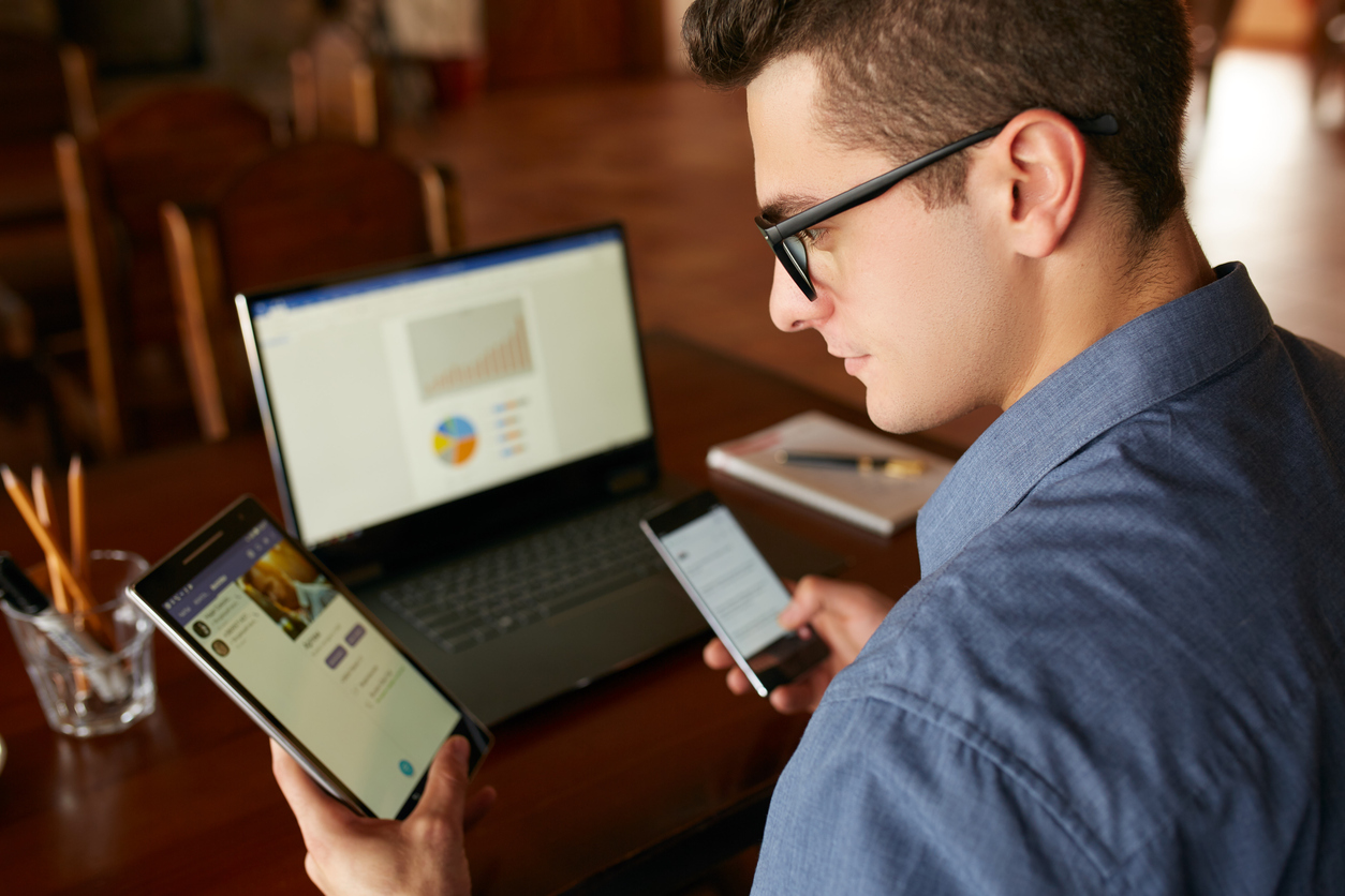 Man in glasses working with multiple electronic internet devices