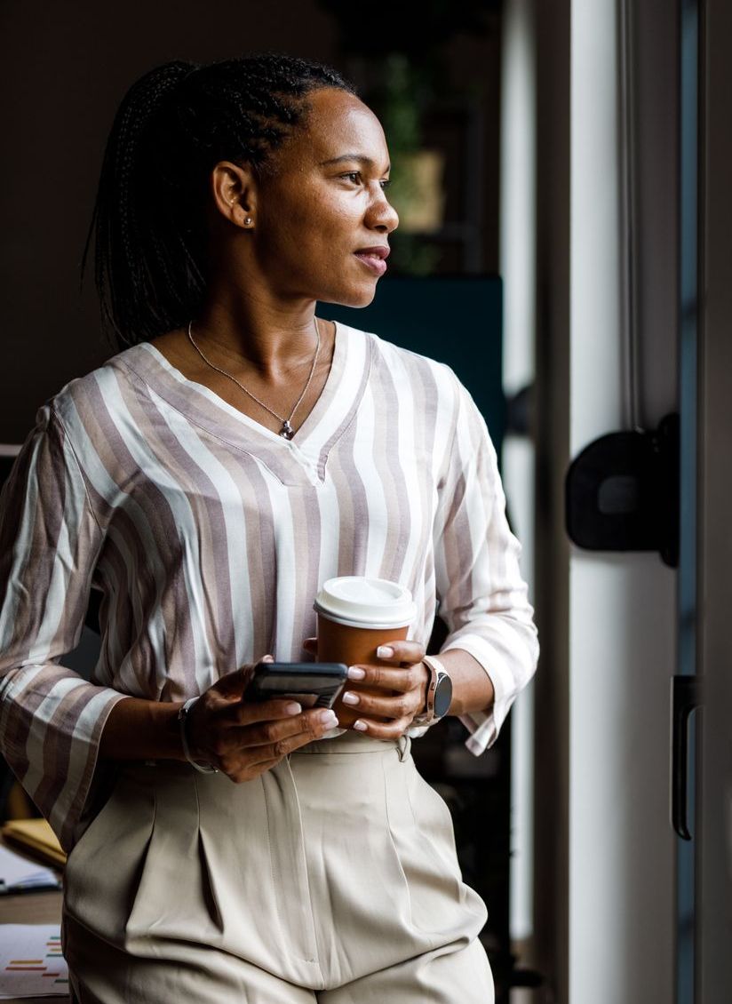 Businesswoman enjoying a cup of coffee by the window during work break