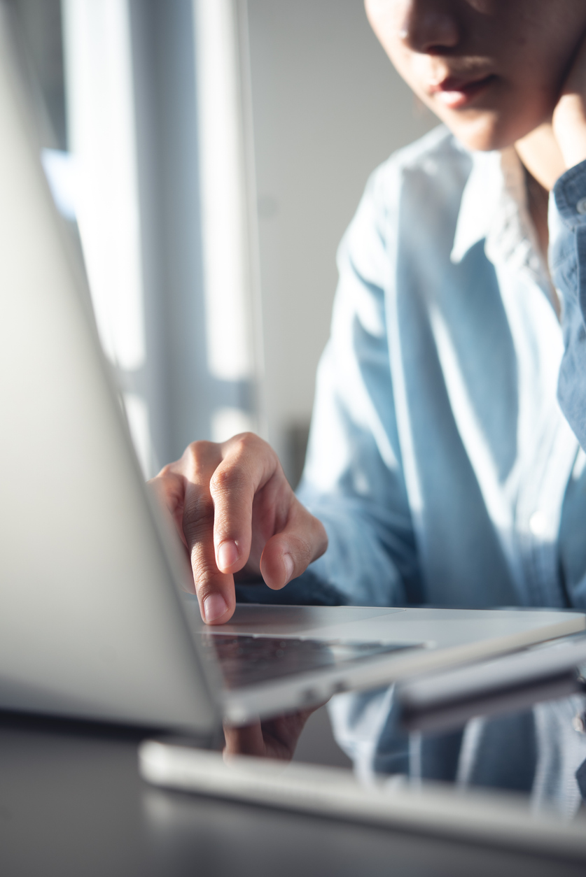 A woman's hands typing on a laptop while sitting at a table