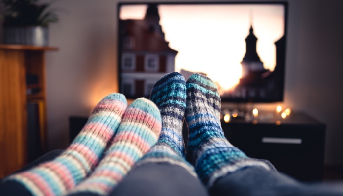 Two sets of cozy socks on a coffee table in front of a television