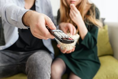Man Holding Remote Control While Eating Popcorn with Woman Watching the Best Streaming Sites for Old Movies
