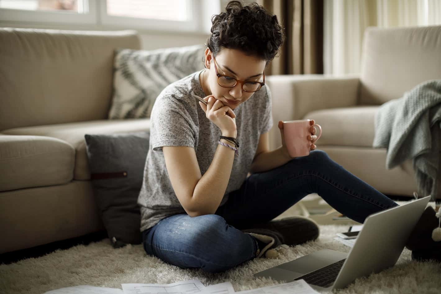 A woman holds a mug of coffee while exploring Xfinity Service Bundles on her laptop