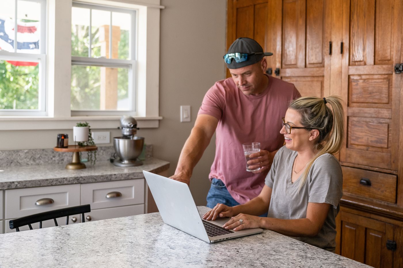 A military service member and his wife look at a laptop in their kitchen while searching for military streaming discounts