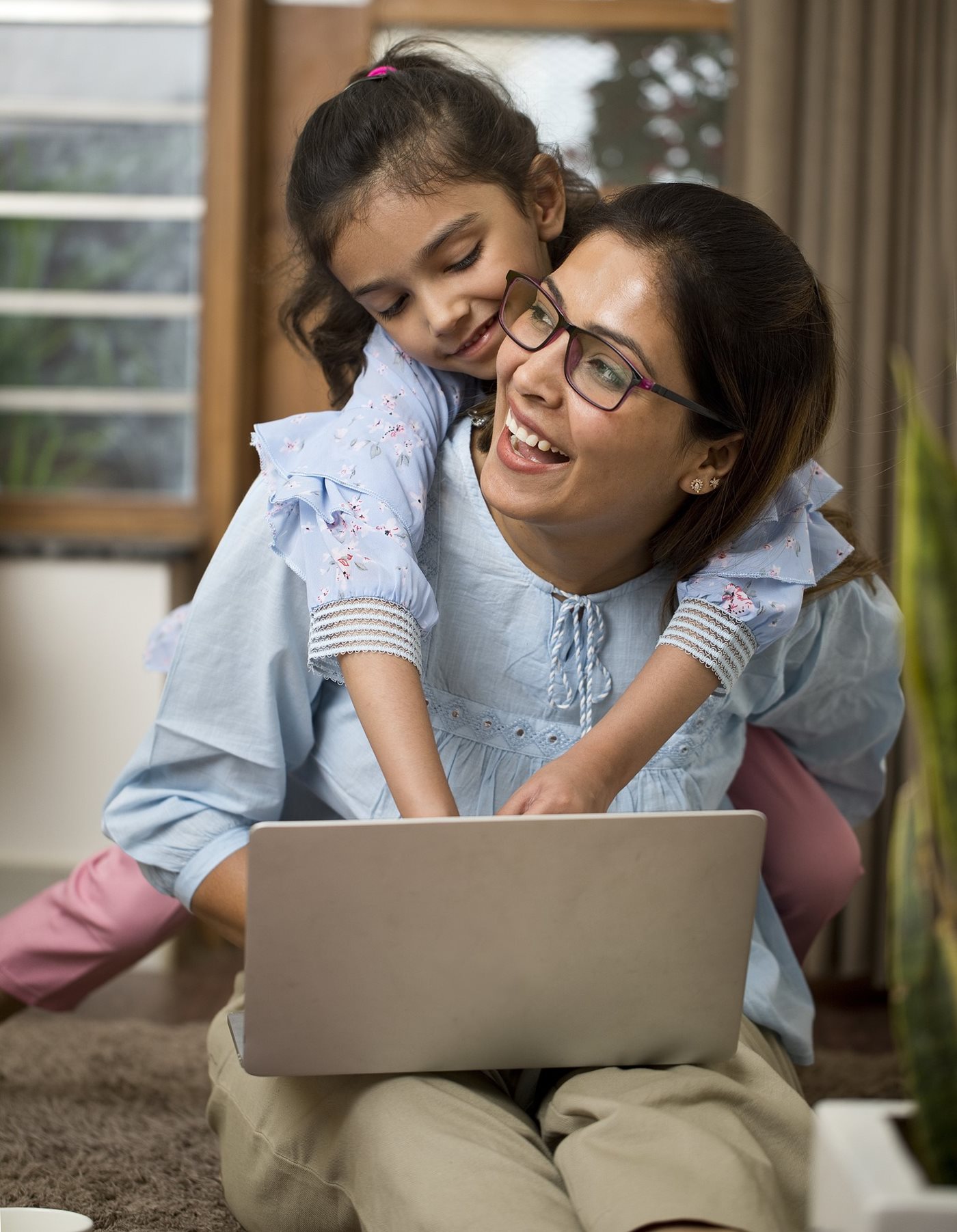 A military spouse smiles as her daughter hugs her while she searches for Internet and TV discounts