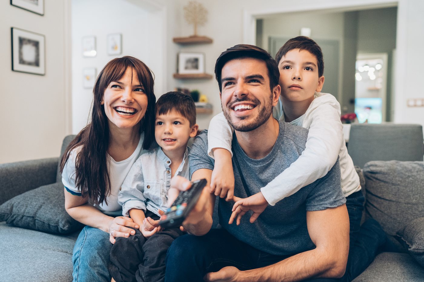 A mother, father and their two sons snuggle on the couch while watching TV powered by Cox