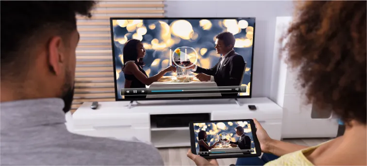 A couple casts a movie onto their TV from their mobile phone