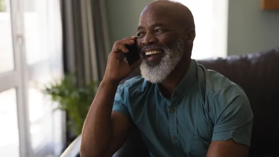 A bearded man laughs while talking on his mobile device