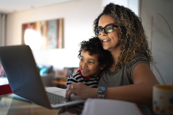 A mother and young son smile while reading installation instructions on a laptop together