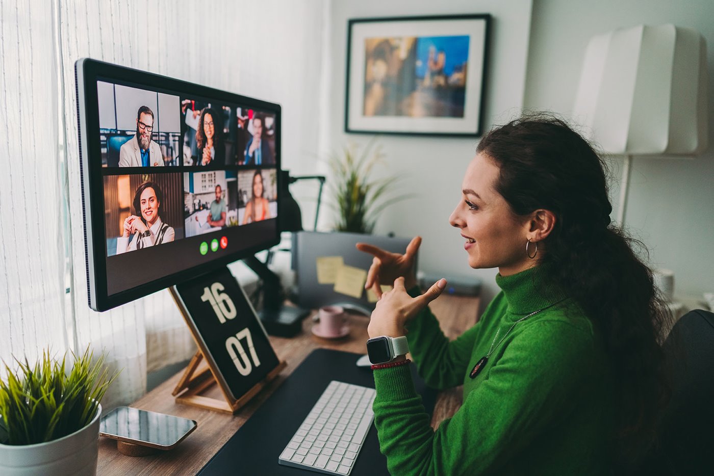 A businesswoman sits at her desk while on a video call with several coworkers