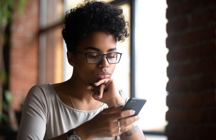 A young woman looks at her mobile phone while testing her Internet speed