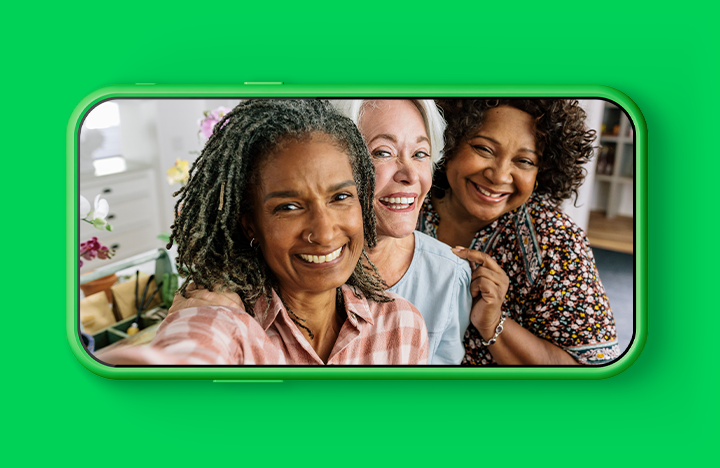 Phone screen with an image of three older friends taking a selfie