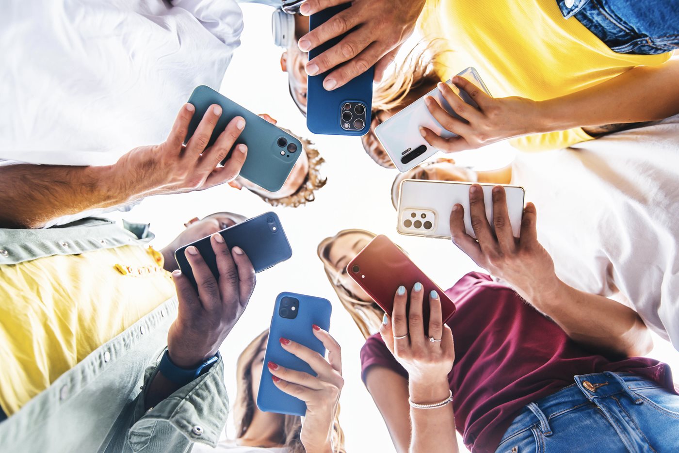 Ground up view of seven individuals looking down at their Androids and Apple iPhones