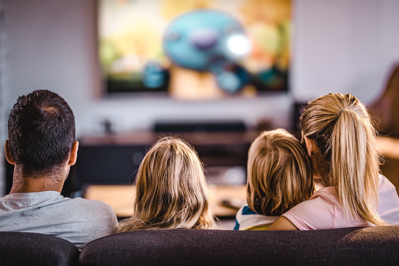 The back of a family's heads as they watch TV powered by Xfinity